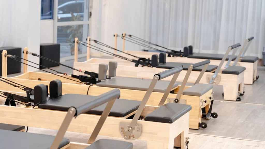 Chair pilates: a woman doing seated, low-impact Pilates on a chair in a calm neutral studio