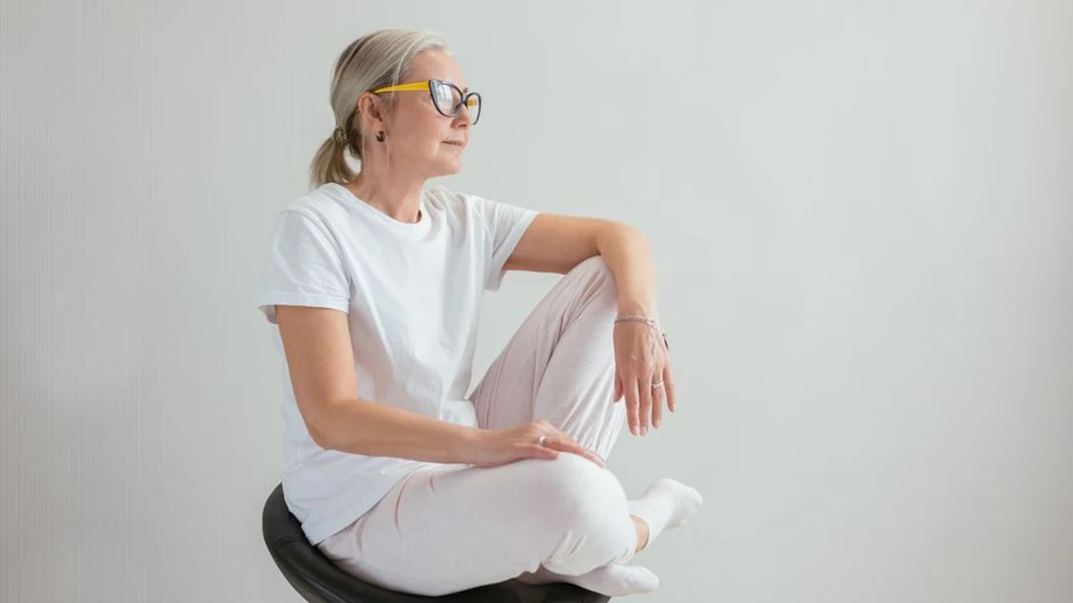 Chair pilates: a woman doing seated, low-impact Pilates on a chair in a calm neutral studio